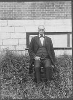SA0089 - Identified on reverse; seated outside unknown building, bushes & tall grass., Winterthur Shaker Photograph and Post Card Collection 1851 to 1921c